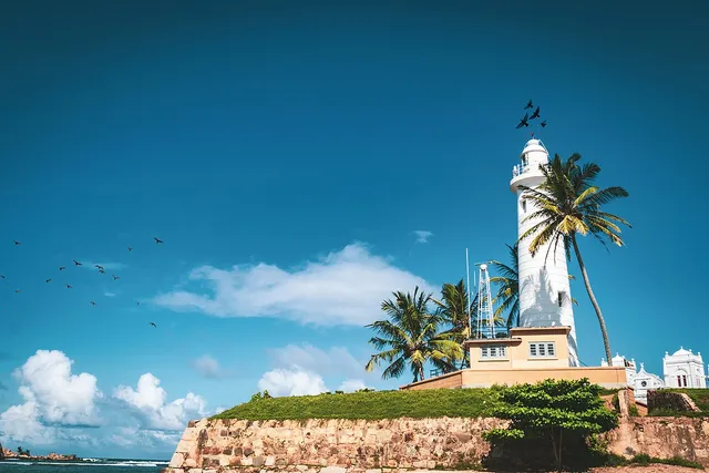 Galle lighthouse and palm trees above the fort walls and sea