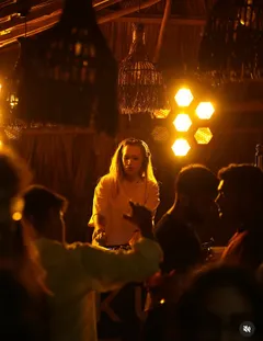 A DJ and guests at a warm-lit party at Hakuna Matata
